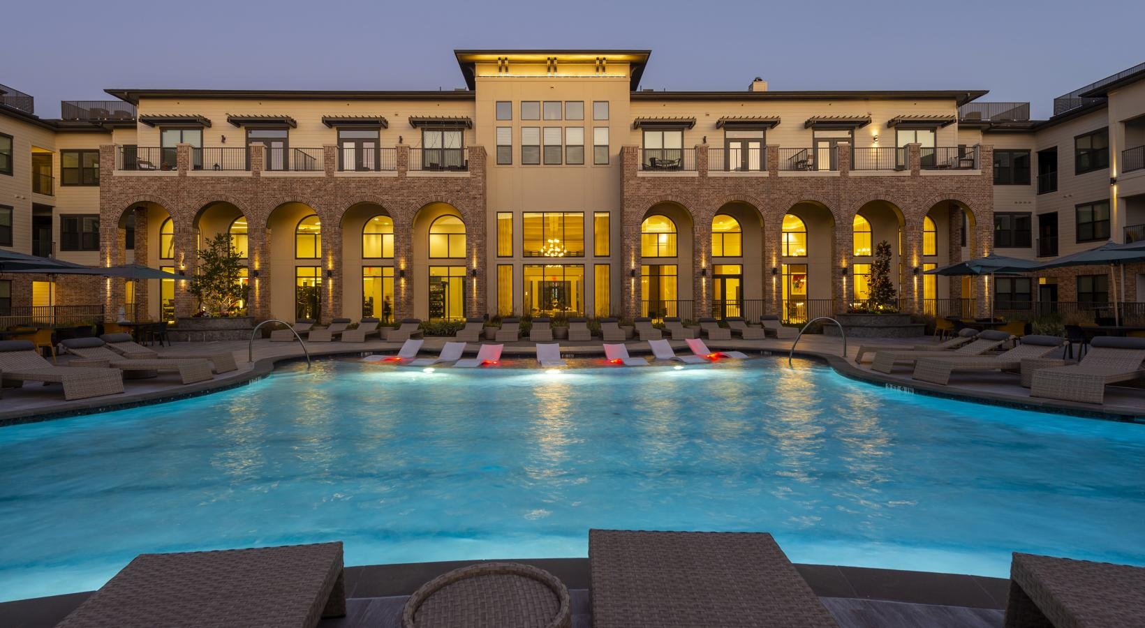 Sparkling swimming pool a large building with a pool in front of it