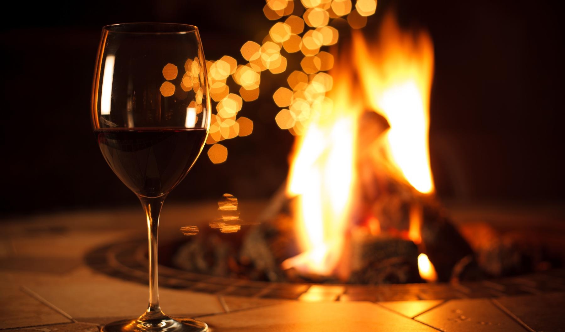 The essence of exceptional living a glass of wine next to a fire