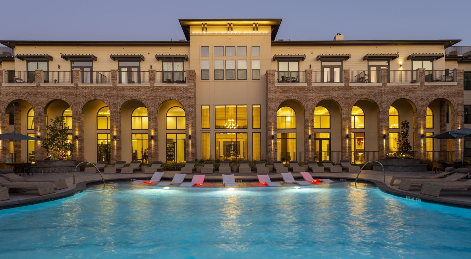 Shimmering resort-style pool a large building with a pool in front of it